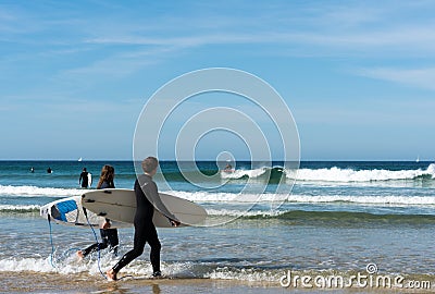 Young surfers walking into the ocean and surfing on the west coast of Brittany in France at Toulinguet Beach near Camaret-Sur-Mer Editorial Stock Photo