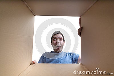 Young surprised man is looking inside cardboard box Stock Photo