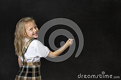Young sweet junior schoolgirl with blonde hair smiling happy writing with chalk in blackboard Stock Photo