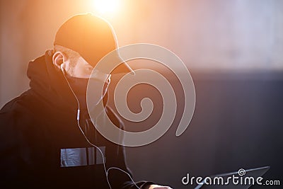 Young talented hacker using laptop computer while working in dark office Stock Photo
