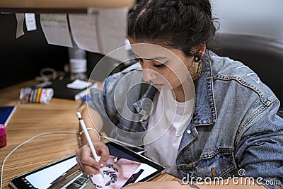 Young tattoo artist drawing her new design on the tablet. Stock Photo