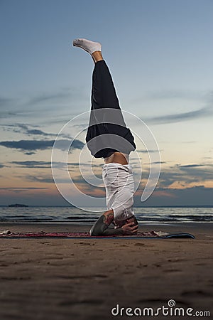 Young tattoo man practicing yoga headstand pose Stock Photo