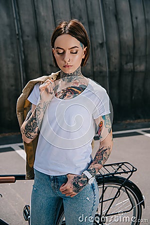 young tattooed woman with closed eyes holding jacket over shoulder Editorial Stock Photo