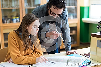 Young teacher helping his student in chemistry class. Education and Tutoring concept. Stock Photo