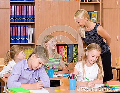 Young teacher helps students of primary school in the exam Stock Photo