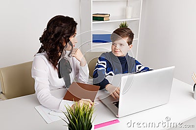 Young teacher with kid doing homework on a computer. Tutor help. Stock Photo