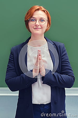 Young teacher prays at the blackboard. Holy woman teacher at school Stock Photo