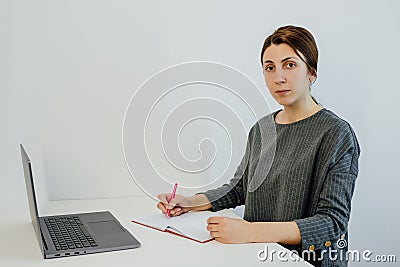 Young teacher Uses Laptop for Learning, Writes Down Useful Information. Stock Photo