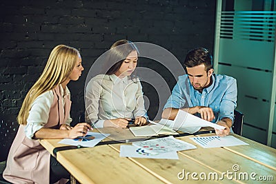 Young team of coworkers watching storyboard for shooting video in modern coworking office. Teamwork process. Horizontal,blurred ba Stock Photo