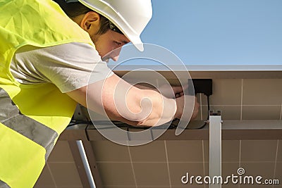 Young technician connecting electrical cables of solar modules. Stock Photo