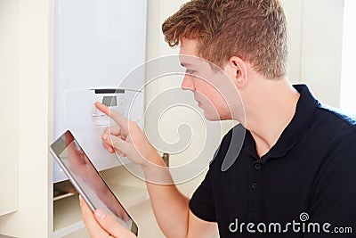 Young technician servicing a boiler, using tablet computer Stock Photo