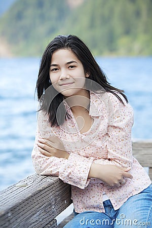 Young teen girl sitting quietly on lake pier Stock Photo