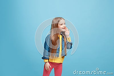 The young teen girl whispering a secret behind her hand over blue background Stock Photo