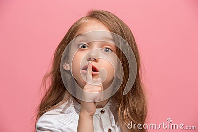 The young teen girl whispering a secret behind her hand over pink background Stock Photo