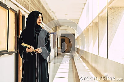 Young teen muslim niqab woman reading the Quran and faith The Holy Al Quran in University building. Arab black chador lady Stock Photo