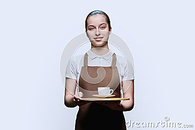Young teenage female waitress holding tray with cup of coffee, on white background Stock Photo