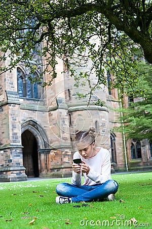 Young teenage girl chatting by smartphone in Glasgow University Stock Photo