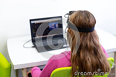 Young teenage girl during EEG neurofeedback session. Electroencephalography concept. Back view. Stock Photo