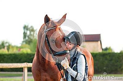 Young teenage girl equestrian kissing her chestnut horse. Stock Photo