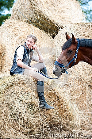 Young teenage girl owner sitting near her red horse Stock Photo