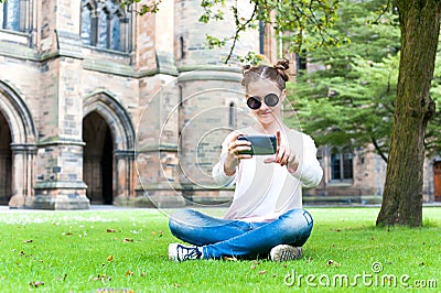 Young teenage girl taking picture in Glasgow University garden. Stock Photo