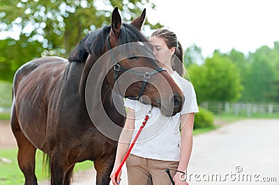 Young teenage girl tenderly kissing her favorite chestnut horse Stock Photo