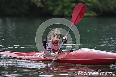 Young teenager girl actively manages a sports kayak boat on a be Stock Photo