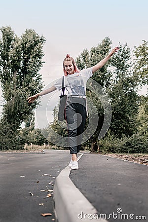 Young teenager hipster girl with pink hair goes along the curb line. Young girl goes his own way Stock Photo