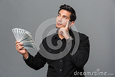 Young thinking concentrated man holding money. Stock Photo