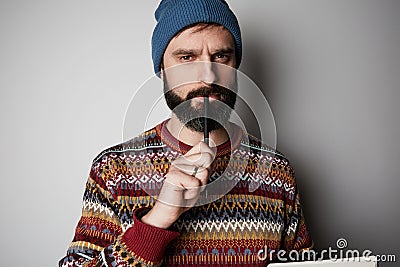 Young thoughtful bearded man in blue beanie thinking about test over empty background. Stock Photo