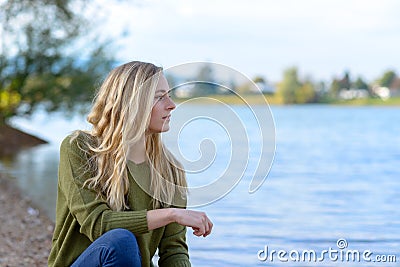 Young thoughtful woman sitting by lake Stock Photo