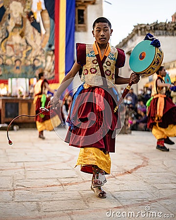 Young Tibetan Buddhist in traditional outfit Dancing holding a Damaru at the Tiji Festival in Nepal Editorial Stock Photo