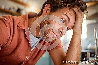 Young tired caucasian businessman working from home alone. One stressed businessman looking unhappy while working at Stock Photo