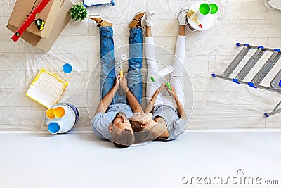 Young tired couple is repairing and painting wall at home Stock Photo