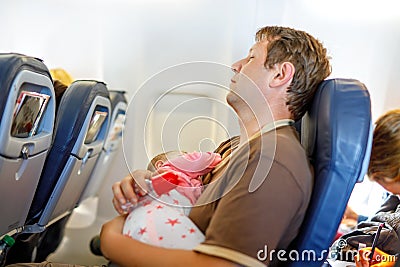 Young tired father and his baby daughter sleeping during flight on airplane going on vacations Stock Photo