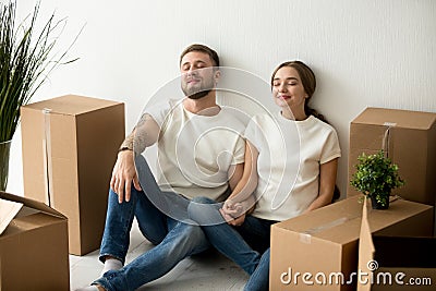 Young tired satisfied couple relaxing on floor with moving boxes Stock Photo