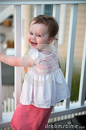 Young toddler girl on patio deck outside at sunset down at shore Stock Photo