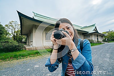 Young tourism lens man taking picture by the camera smiling. joyful attractive professional photographer using digicam shot. Stock Photo