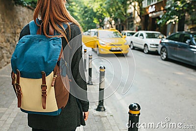 A young tourist girl with a backpack in the big city is waiting for a taxi. Journey. Sightseeing. Travel. Stock Photo