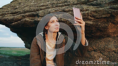 Young tourist woman backpacker photographing landscape on her smartphone camera after hiking on rock at sunset Stock Photo