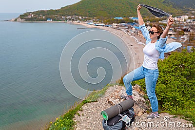 A young tourist woman climbed to the top of the mountain. Emotions of joy and happiness. Mountain and sea in the background. Copy Stock Photo