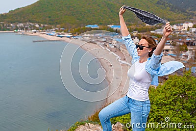 A young tourist woman climbed to the top of the mountain. Emotions of joy and happiness. Mountain and sea in the background. Close Stock Photo