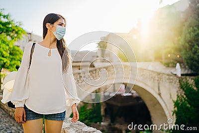 Young tourist woman with face mask travelling to European cities during coronavirus pandemic outbreak. Travel to Europe amid COVID Stock Photo