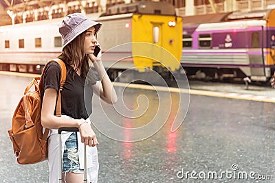 Young tourist woman holding cellphone and call Find accommodation on railway station. Travel concept Stock Photo