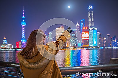Young tourist woman pointing a finger at the bund in shanghai, china. Stock Photo