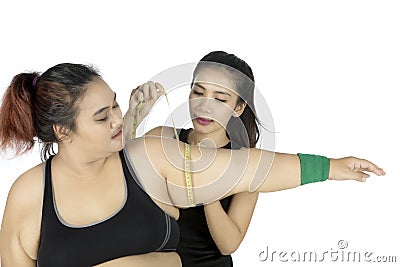 Young trainer measuring bicep of fat woman Stock Photo