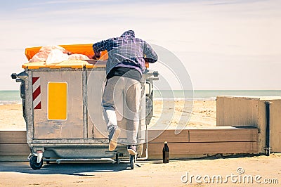 Young tramp rummaging in trash container looking for food and re Stock Photo