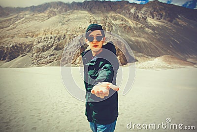 Young travel man lending a helping hand in outdoor mountain scene Stock Photo