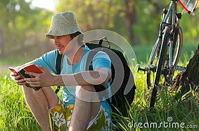 Young traveler with bicycle reading the book Stock Photo