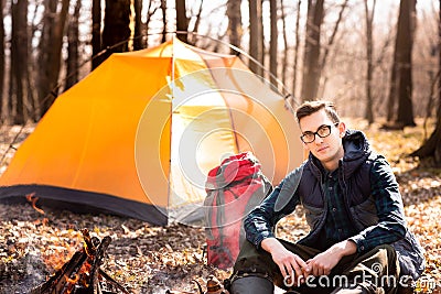 A young traveler in the forest is resting near the tent and cooked breakfast in nature Stock Photo